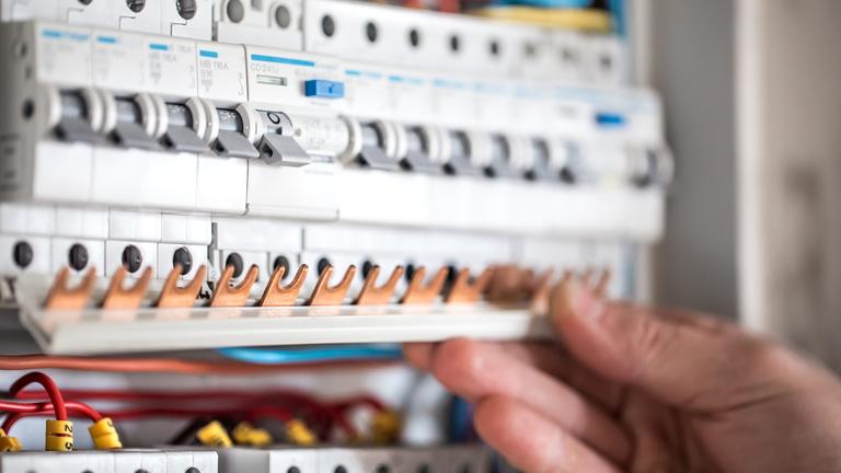 man-electrical-technician-working-switchboard-with-fuses-installation-connection-electrical-equipment-close-up